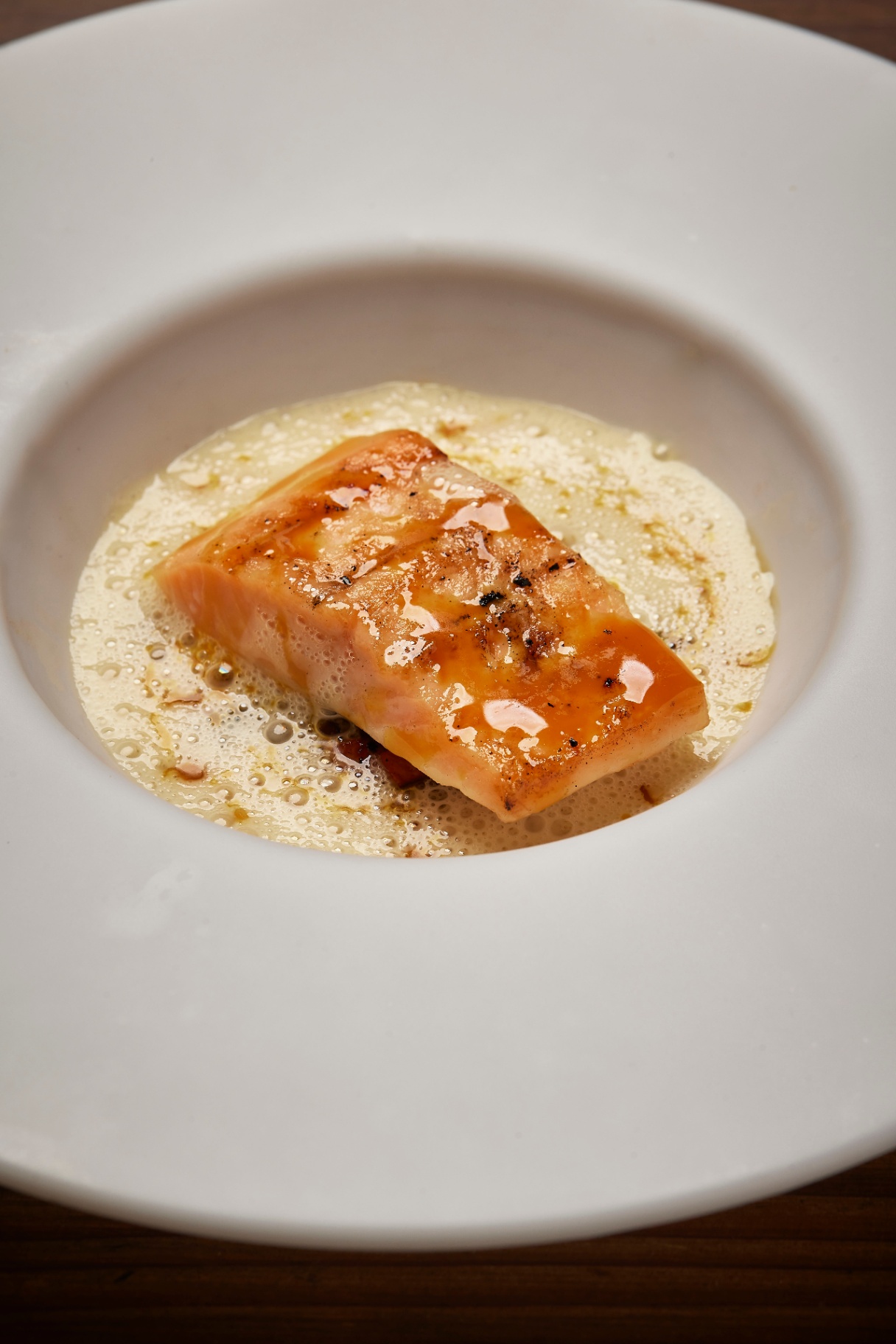Grillet laks serveret i skummende sauce i dyb tallerken