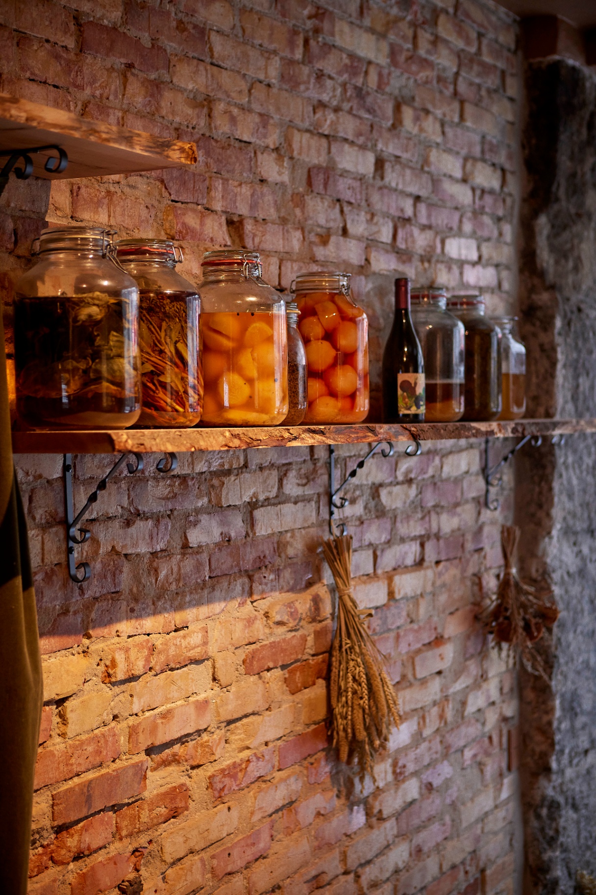 Krukker med fermentering og flasker på murstensvæg i Restaurant Grim