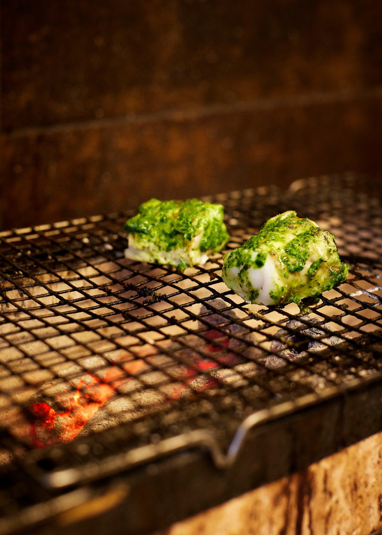 Cod with green herb marinade grilling over embers